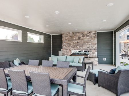 Pool cabana with 8 person eating table, couch, 2 chairs, and fireplace