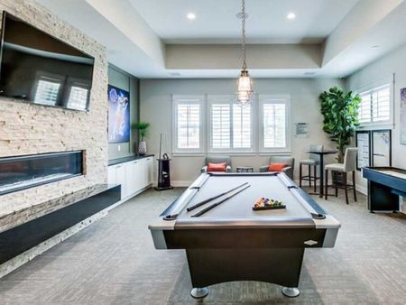 Game room with billiards table, shuffleboard, flat screen television, and fireplace