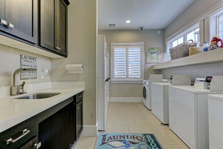 Laundry area with 4 washers, 6 dryers, cabinets, and spacious sink and counter area