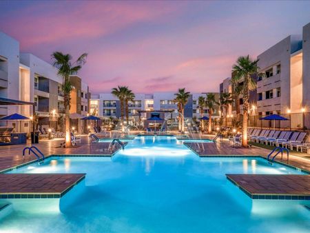 Pet-Friendly Apartments In Glendale, AZ - Acero At The Stadium - Resort-Style Pool With Lounge Chairs, Palm Trees, And Umbrellas.