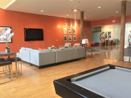 Community room with pool table, comfortable seating, large flat screen TV, and plenty of room at Washington Mill 240 apartments in Lawrence, MA.