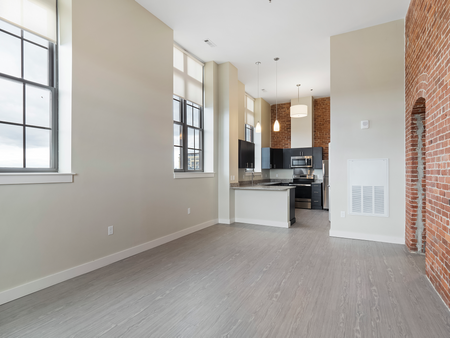 Open-Concept Living Area featuring large windows and interior brick walls at Washington Mill 240 | Lawrence Apartments