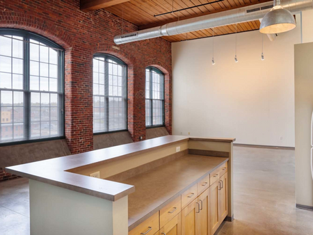Large windows in brick walls with demo kitchen in community space at Washington Mill 240 | Apartments Lawrence, MA.