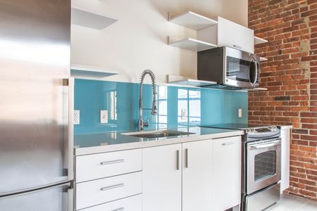 Modern Kitchen with stainless steel appliances, high neck faucet, brick interior wall | 381 Congress Lofts | Apartments in Downtown Boston For Rent