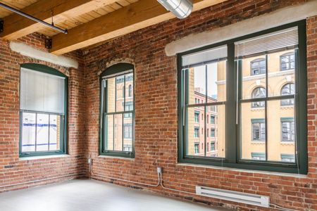 Large living area with exposed brick walls, and wooden beam ceiling |  381 Congress Lofts | Apartments in Downtown Boston