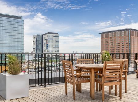 Outdoor seating on wood-plank deck with city view | 381 Congress Lofts | Apartments For Rent in Boston