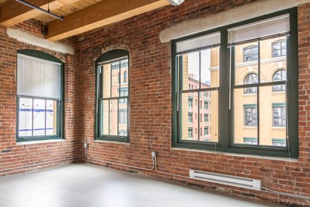 Airy living area with room to entertain featuring exposed brick walls, large windows, and exposed beam ceilings | 381 Congress Lofts | Apartments For Rent in Boston