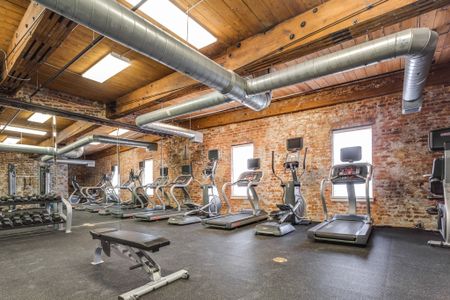 View of Fitness Center, Showing Cardio Machines, Free Weights, and Bench at Alpha Mill Apartments