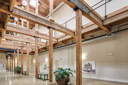 View of Hallway, Showing Wood Beams in Structure, Benches, and Plants at Alpha Mill Apartments