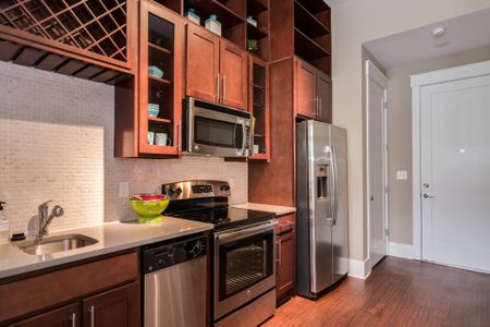 View of Kitchen, Showing Plank-Wood Flooring, Stainless Steel Appliances, and Custom Cabinetry at Alpha Mill Apartments