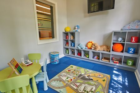 View of Children's Activity Room, Showing Table With Chairs, Games, Cubbies, and Window Into Sport Court at Cottonwood Reserve Apartments
