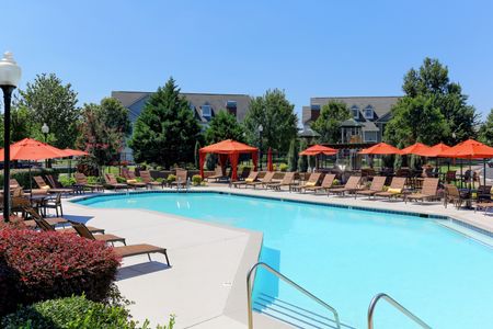 View of Resort-Style Pool, Showing Expansive Sundeck, Lounge Chairs, and Tables With Umbrellas at Cason Estates Apartments