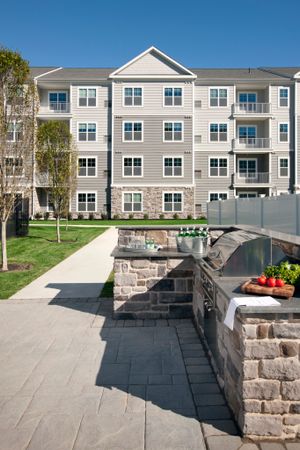View of Grilling Lounge, Showing Grill, Prep Area, and Apartment Building in the Background at Parc Westborough Apartments