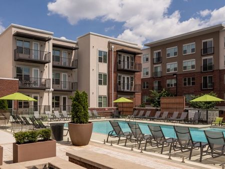 View of Pool Area, Showing Loungers, Fenced-In Area, and Apartment Buildings in Background at The Melrose Apartments