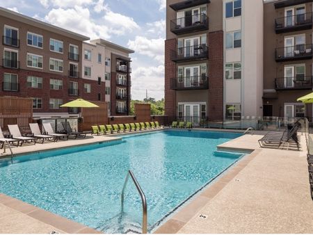 View of Pool Area, Showing Fenced-In Area, Loungers, and Apartment Buildings Surrounding at The Melrose Apartments