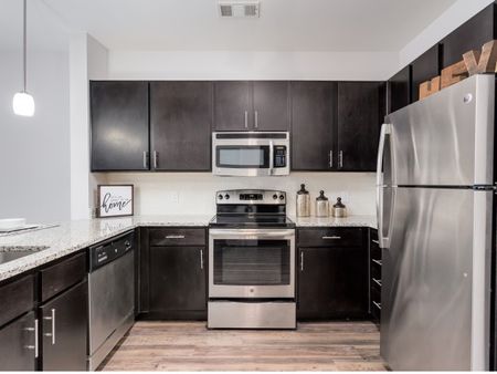 View of Kitchen, Showing Plank Wood Flooring, Granite Countertop, and Stainless Steel Appliances at The Melrose Apartments