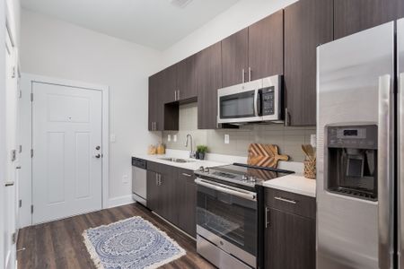 View of Kitchen, Showing Plank Wood Flooring, Back Splash Tile, and Stainless Steel Appliances at The Melrose Apartments