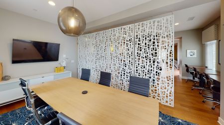 View of private conference room with large flat-screen tv, showing white see-through partition wall and conference desk and chairs
