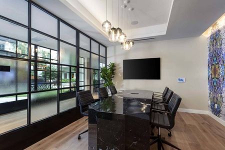 Glass walled partitions and conference tables with smart TV and striking art at Modera San Diego apartments.