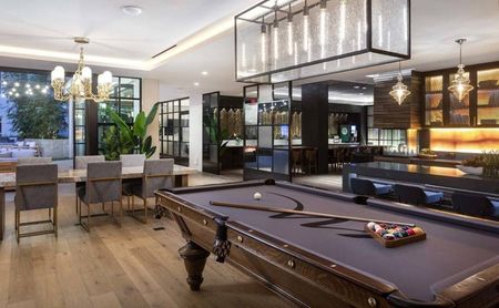 Billiards table with lounge area and private offices and outdoor lounge beyond at Modera San Diego apartments.