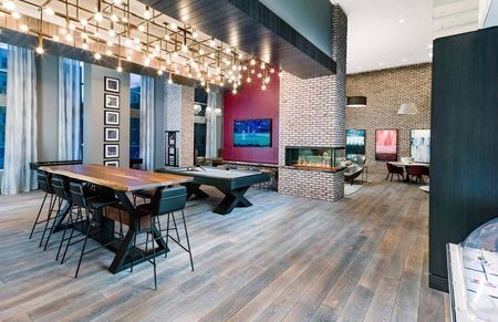 Light installation above bar top tables next to a pool table and arcade game area with kitchen space at Modera Founders Row apartments in Falls Church
