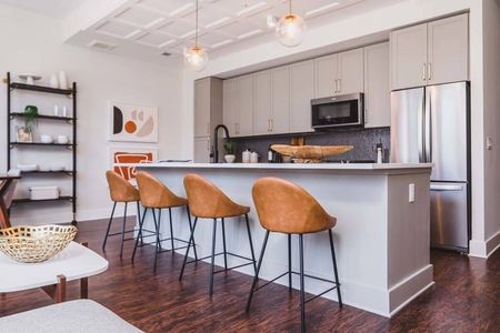 Large kitchen island with pull-up bar seating and white cabinets in background in a Modera Old Ivy apartment.