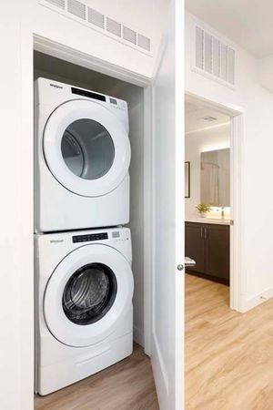 Full-size washer and dryer next to bathroom at a Modera San Diego apartment.
