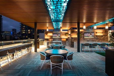 Stylish blue lighting creates a chic atmosphere at the rooftop entertainment lounge complete with outdoor kitchen, TV and plenty of seating at Modera San Diego apartments.