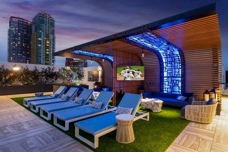 Blue lighting features in seating area create a lounge-like feel on the rooftop pool deck next to chaise lounge seating at Modera San Diego apartments.