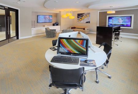Business center with 3 computers and table with chairs