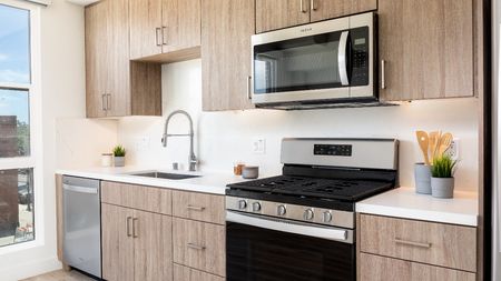 Ash Brown Kitchen Option with large moveable island, Modern Cabinets, Stainless Steel Appliances, quartz countertops and backsplash at a Modera San Diego apartment.