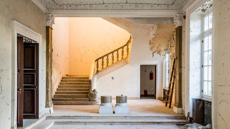 Before: Ornate staircase lit from 2nd level during the renovation