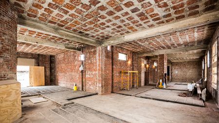 L shaped room with exposed brick during renovation