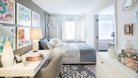 Bright and open bedroom with queen size bed, dresser, and desk
