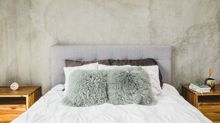 Bedroom with concrete wall featuring queen size bed and two nightstands