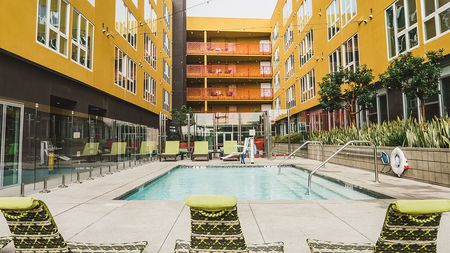 Splash pool with lounge seating amidst apartment building exterior surrounding