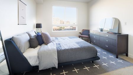Bedroom with blue accents featuring Queen bed, full size dresser, and accent chair