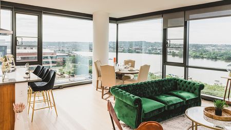 Apartment interior with green velvet sofa overlooking river