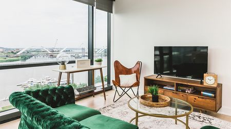 Living room with green velvet sofa, TV, and views of the Anacostia River