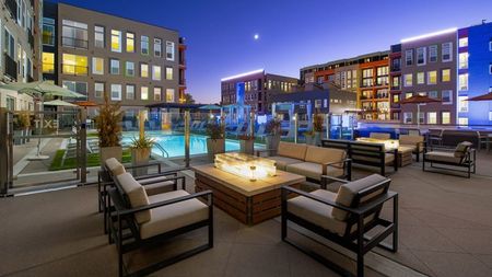 Outdoor firepit and chairs on pool deck at night