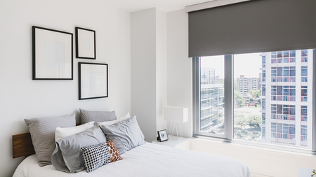 Bedroom with white bed, grey pillows and large window