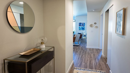 Hallway with console table and round mirror and hardwood floors
