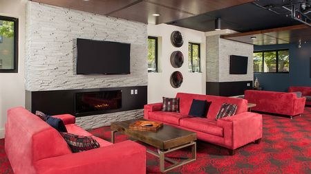 Resident lounge featuring social seating around a fireplace and wall mounted television