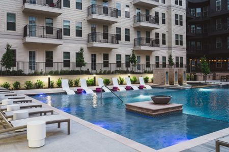 Nighttime view of luxury pool with lounge seating, sundeck, pool island at Modera Frisco Square apartments