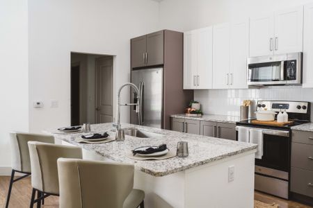 Two-tone cabinets with dark gray cabinets below and white cabinets above and a large kitchen island in a Modera Frisco Square apartment