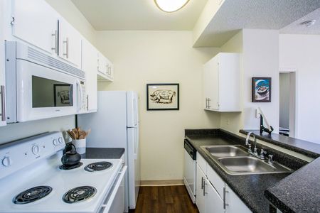 Apartments in North Las Vegas for Rent - Desert Ridge - Galley Kitchen with White Cabinetry, Grante Countertops, Wood Plank Flooring, and All White Appliances