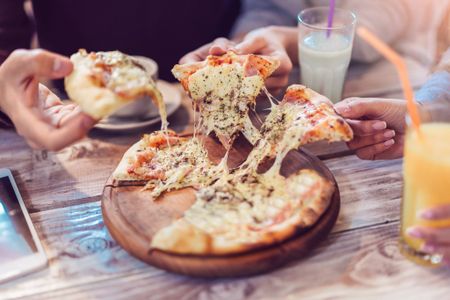 Friends sharing a pizza and each taking a slice.