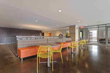 Resident lounge at our apartments for rent in Michigan, featuring bench seating, tables, chairs, and colorful decor.
