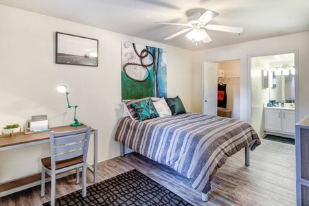 Model bedroom at our student living apartments in Orlando, featuring wood grain floor paneling and a desk.