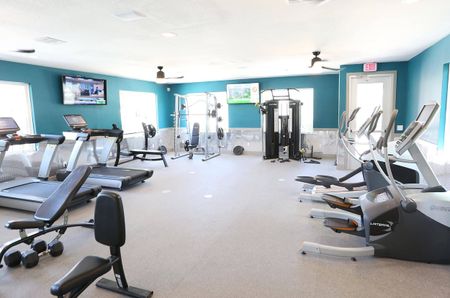 Fitness center at our apartments for rent in Orlando, featuring treadmills, bench press, and free weights.